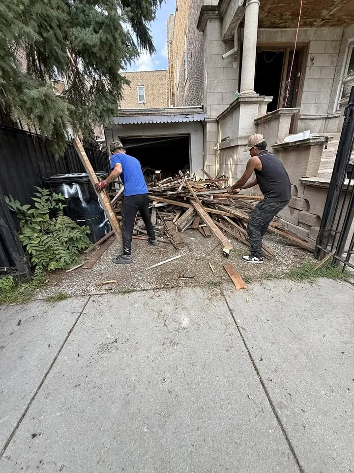 Workers clearing timber beside a garage
