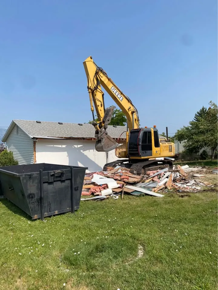 Excavator working beside a partially demolished structure