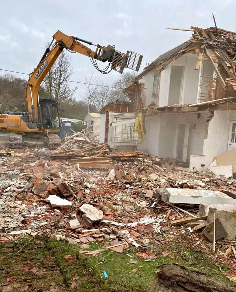 Excavator removing part of a low-rise structure