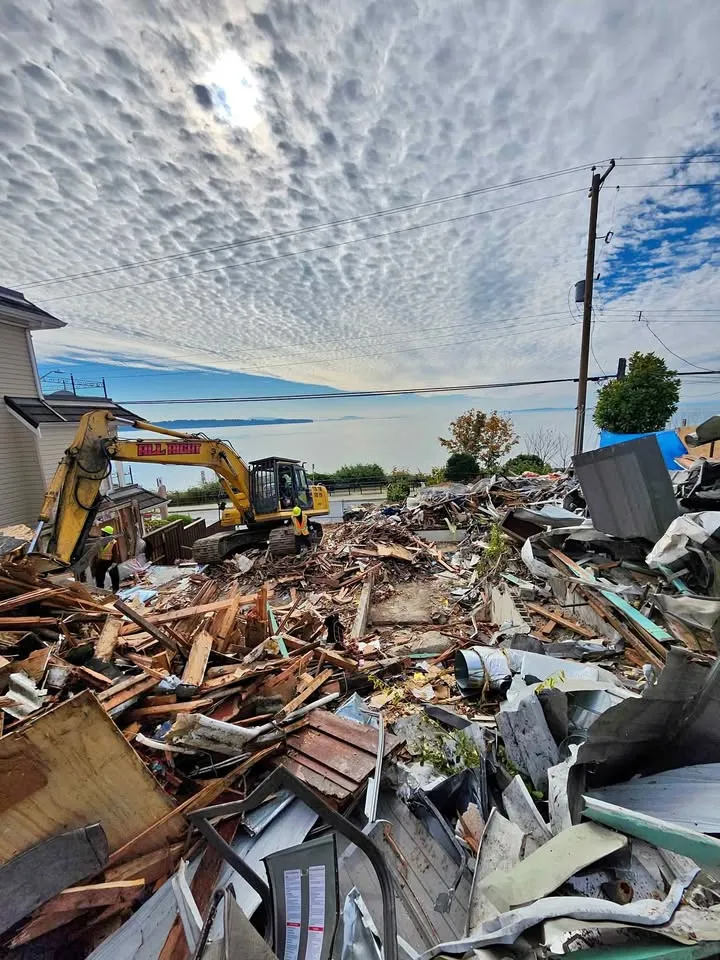 Excavator beside a pile of structural debris
